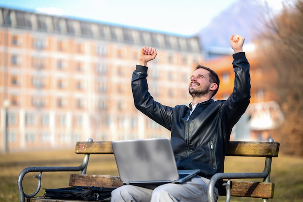 A very cheerful man celebrating victory sitting on a bench.