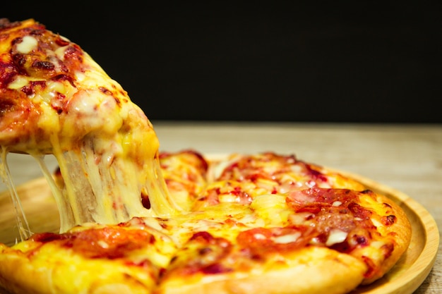 Very cheesy pizza slice in hand.Hot pizza slice with melting cheese 