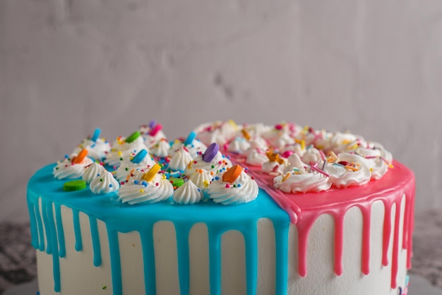 Very colorful cake decorated with blue and pink icing on a cement table