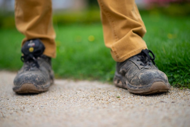 Very dirty working man shoes on background in the park