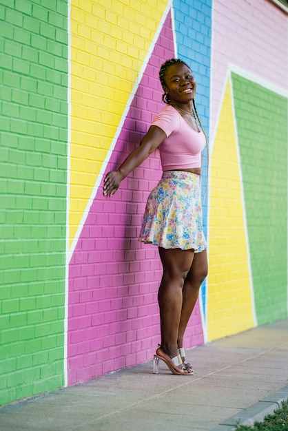 Very happy black African woman walking and posing on a wall of many colors. Lifetyle photo of a happy African woman