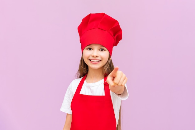 A very joyful girl in a chef's costume smiles a girl in a chef's hat on an isolated background