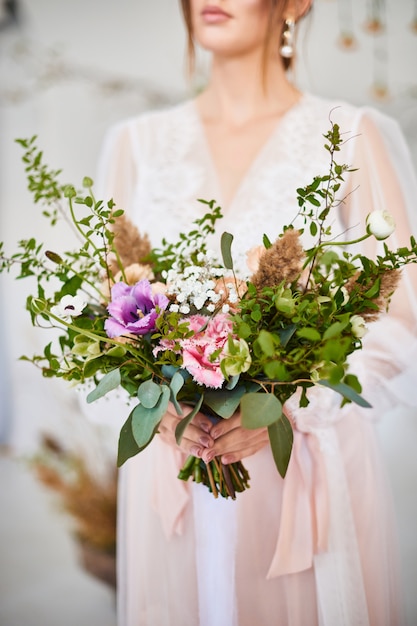 Very nice young woman holding big and beautiful colorful flower wedding bouquet. Morning bride