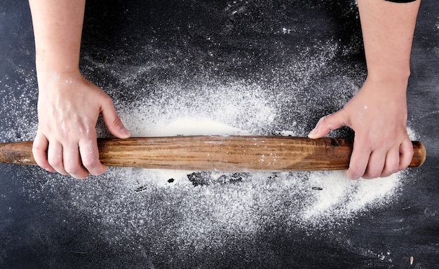 Very old brown wooden rolling pin in female hands