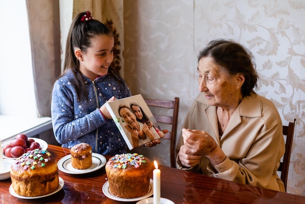 very old grandmother and granddaughter color eggs, preparing Easter cake for Easter at home.