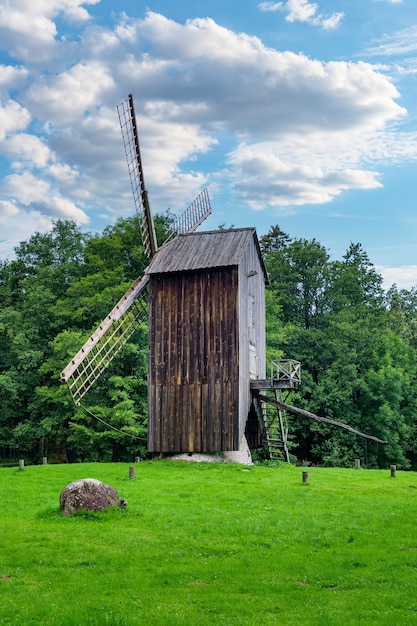 Very old wooden windmill on green grass field.