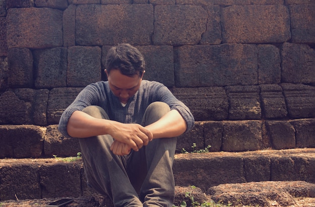 a very sad and depressed man sitting near a wall