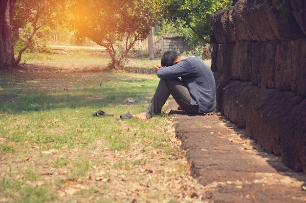 a very sad and depressed man sitting near a wall