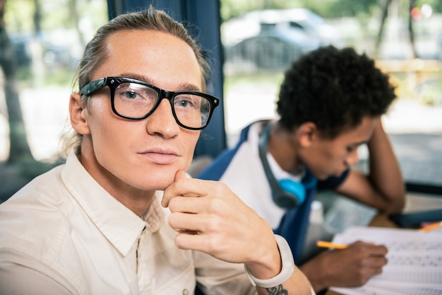 Very smart. Portrait of a serious young man looking at you while having a class