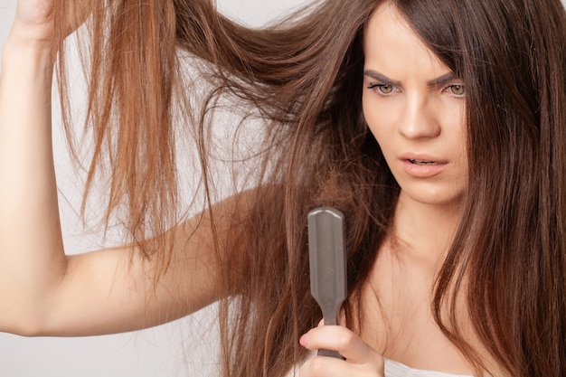 Very upset young woman with comb and problem loss hair.