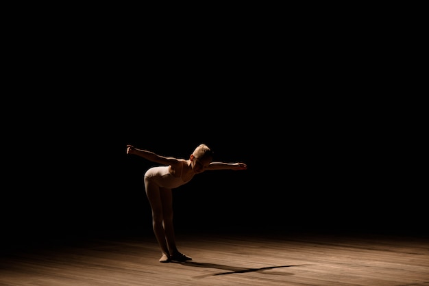 Very young ballerina posing on a black background