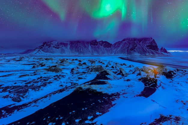 Vestrahorn mountaine on Stokksnes cape with Green northern lights and reflections. Amazing Iceland nature seascape. Iconic location for landscape photographers and bloggers. Scenic Image of Iceland