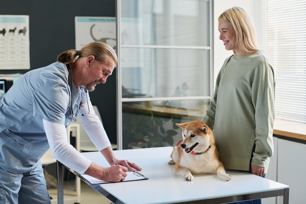 Photo vet doctor writing prescription for his canine patient