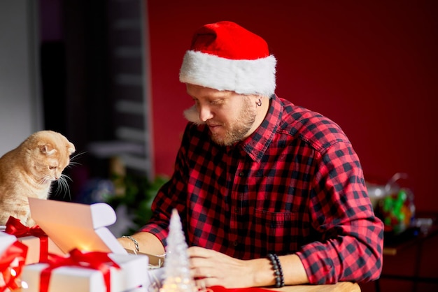 Vet Man in Santa hat and cat in hand making greeting card for New Year and Christmas