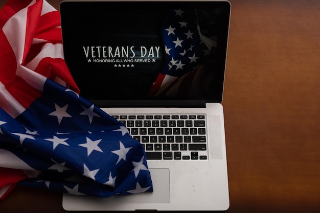 Veterans day written in laptop with flag of the United States, on a rustic wooden background