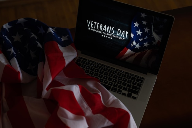 Veterans day written in laptop with flag of the United States, on a rustic wooden background