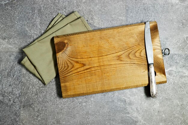 vhandmade wooden cutting board with napkin on gray grunge marble background