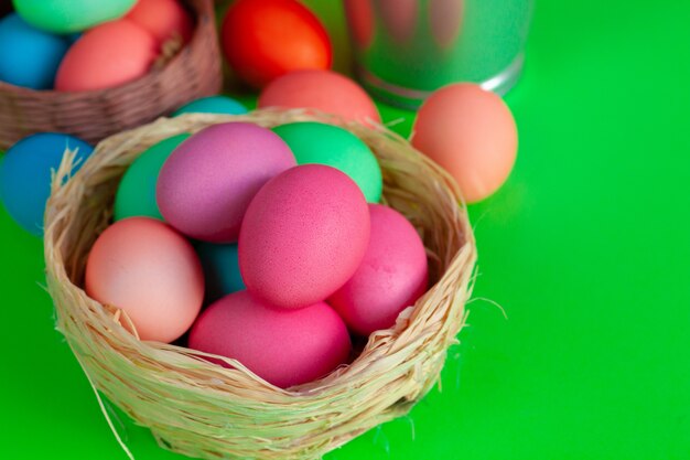 Vibrant colored eggs in a nest on green. Easter concept