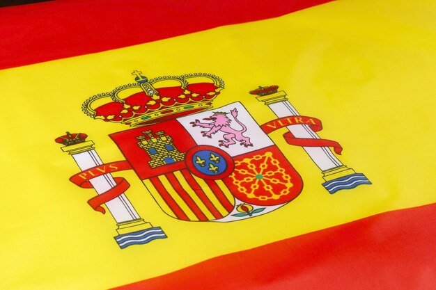 Photo the vibrant flag of spain featuring the royal coat of arms on a bright red and yellow background