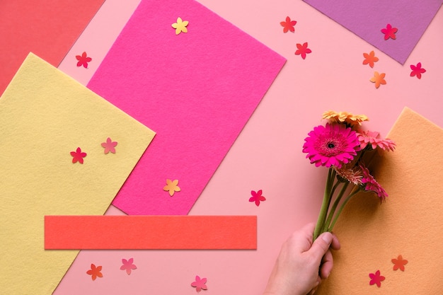 Vibrant flat lay with gerbera daisy flowers on coral color paper. Creative flat lay, toned image.