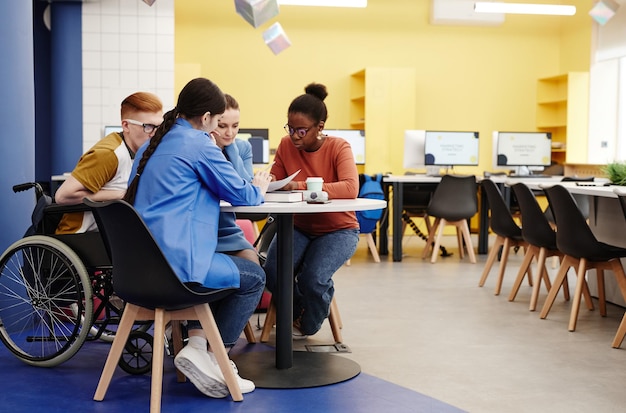 Vibrant full length shot of diverse group of students studying together at table in college lab copy