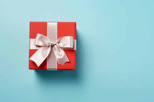 Vibrant red gift box decorated with white satin ribbon and bow against a pastel blue backdrop