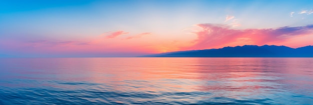 Vibrant sunset over calm waters with distant mountains on the horizon in serene coastal setting