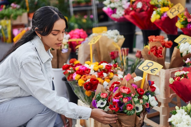 Vibrant young Latina happily selecting colorful blooms from a street vendor in a beautiful city