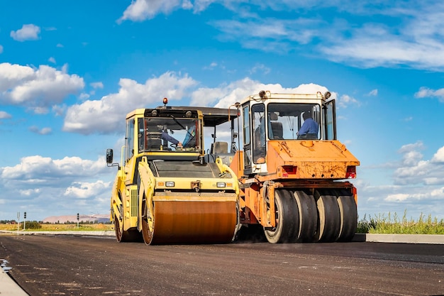 Vibratory road roller lays asphalt on a new road under construction Closeup of the work of road machinery Construction work on the construction of urban highways