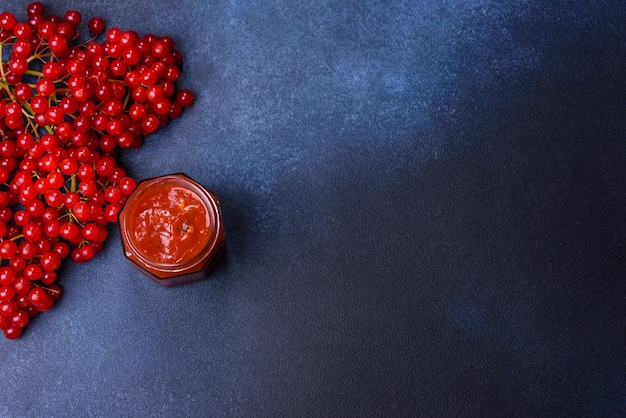 Viburnum fruit jam in a glass jar on a dark concrete background