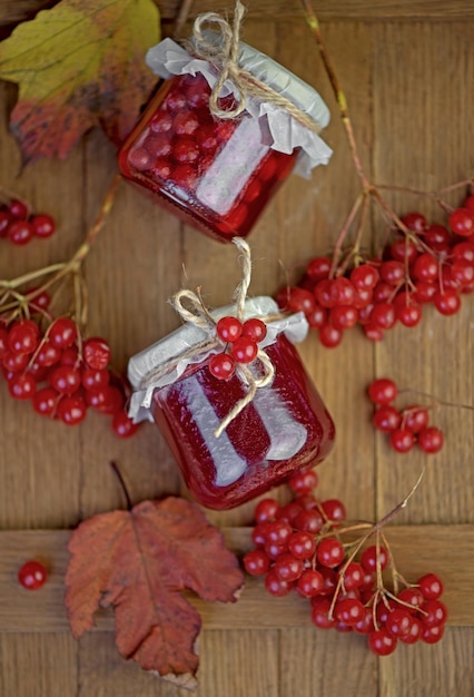 Viburnum fruit jam in a glass jar on a wooden table near the ripe red viburnum berries Source of natural vitamins Used in folk medicine Autumn harvest