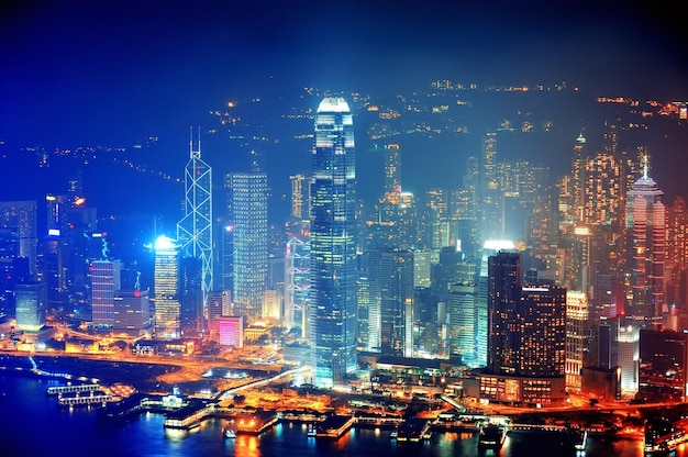 Victoria Harbor aerial view with Hong Kong skyline and urban skyscrapers at night.