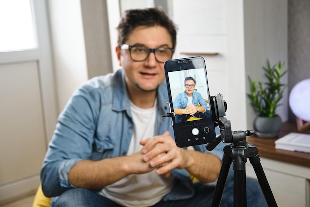 Video blogger recording content to channel at home before smartphone fixed on tripod