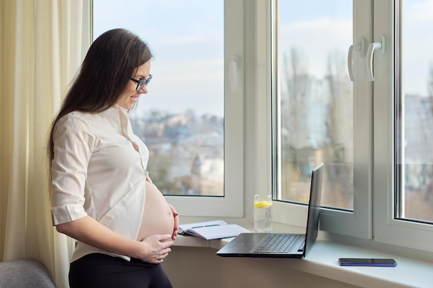 Video chat call pregnant happy woman showing big belly in laptop webcam