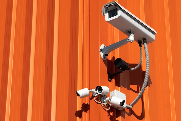 Video surveillance cameras installed on the red wall at the entrance to the supermarket Security and antitheft systems