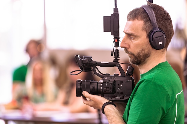 Videographer shooting a film or a television program in a studio with a professional camera, backstage