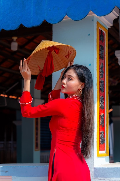 Photo vietnamese girl with ao dai dress standing in traditional house of vietnam text in photo mean best wishes to family happiness prosperity health tet holiday and new year