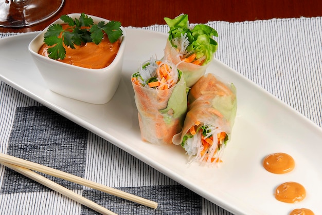 Vietnamese rolls rice paper roll with vegetables and chipotle chili dressing on wooden table food