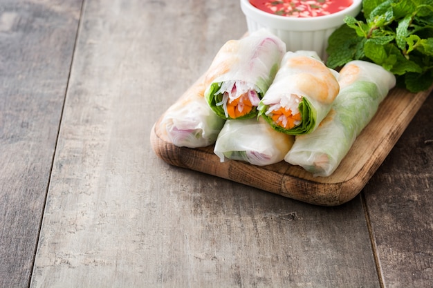 Vietnamese rolls with vegetables, rice noodles and prawns on wooden copy space