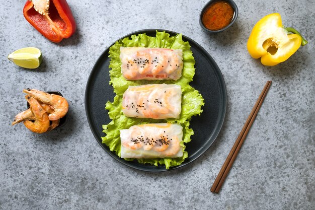 Vietnamese spring rolls with prawns and ingredients in rice paper on grey background. View from above. Asian cuisine. Horizontal orientation.