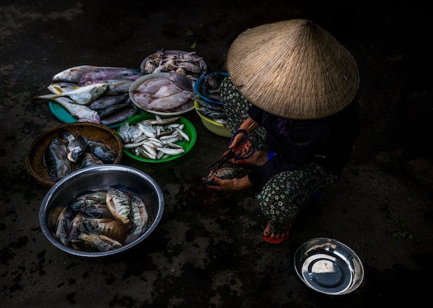 Vietnamese woman cleaning fish to sell at a public market