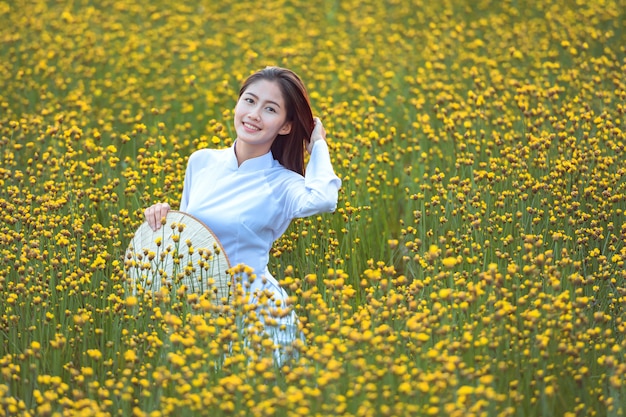 Vietnamese women In traditional national dress Watching yellow flower garden