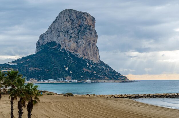 Photo view of the beach of calpe at sunrise with the penon de ifach in the background alicante province spain