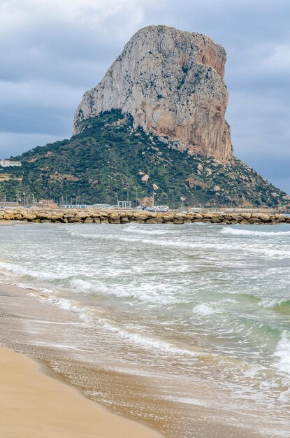 Photo view of the beach of calpe at sunrise with the penon de ifach in the background alicante province spain