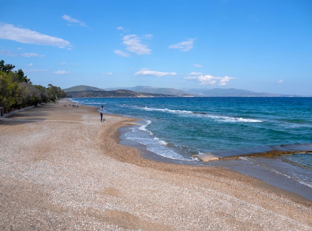 View of beach and sea with tourists in resort town Tolo in Peloponnese in Greece