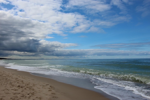 view of beach and sea with white wave foam on a clear sunny day Baltic Sea