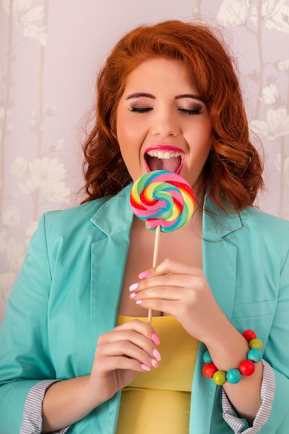 View of a beautiful redhead girl with a lollipop candy wearing colorful clothing.