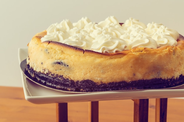 View of a black biscuit and cream cake on a white wall