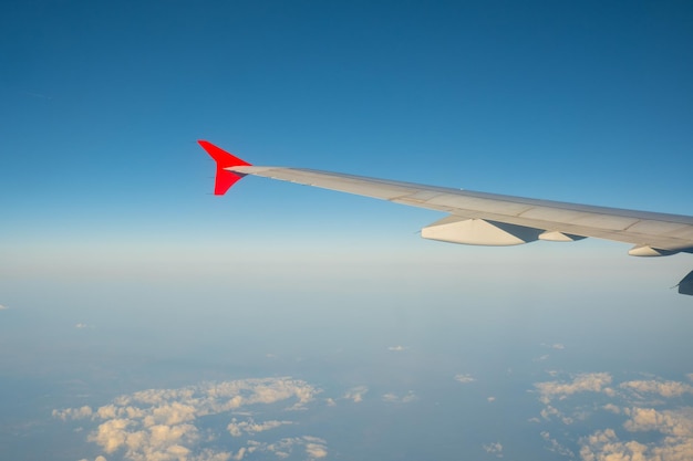 View of the blue clear sky from the height of flight above the clouds from the window of the plane