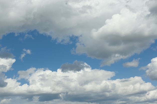 View of the blue sky with thick white clouds. Dense cumulus cloud cover. Summer day, nature. Soft focus. Artificial noise. Background.